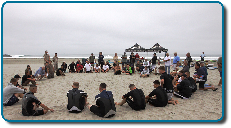 This photo depicts a large group of people sitting in a circle on the beach.