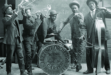 A photograph shows a group of black jazz musicians playing their instruments. A drum reads “Jazzing Orchestra / King and Carter / Houston Tex.”