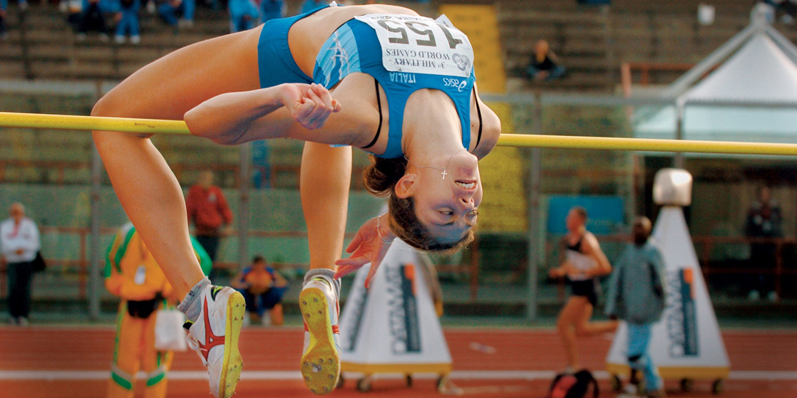 Illustration shows a woman, upside-down with an arched back, going over a pole vault.