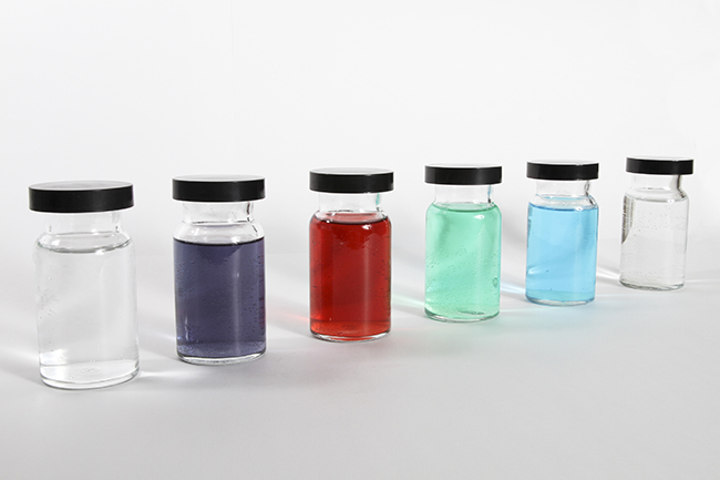 This figure shows six containers. Each is filled with a different color liquid. The first appears to be clear; the second appears to be purple; the third appears to be red; the fourth appears to be teal; the fifth appears to be blue; and the sixth also appears to be clear.