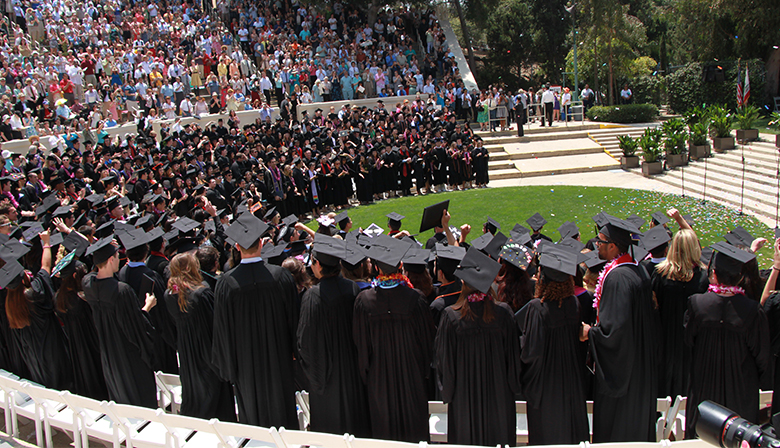 This is a photograph of students at their outdoor college graduation ceremony.