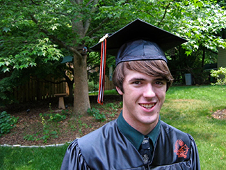 A photo shows a smiling person wearing a graduation cap and gown.