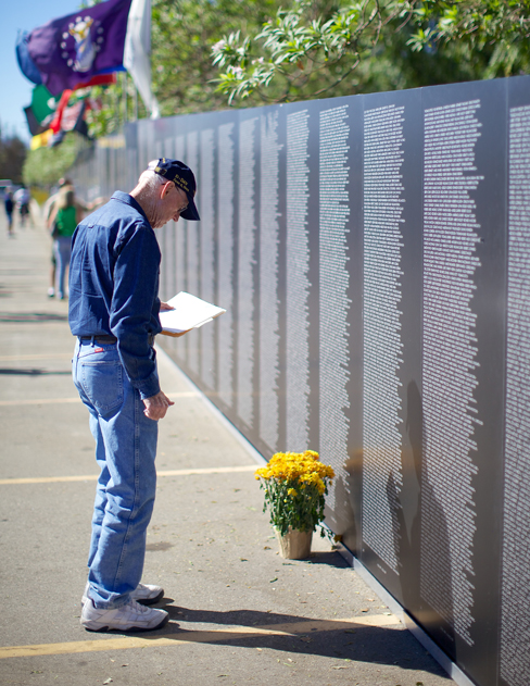 A photograph shows a person looking at the Vietnam Traveling Memorial Wall.