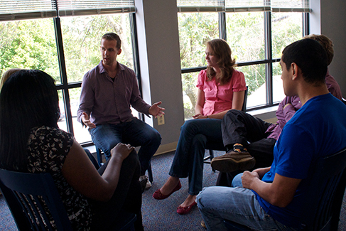 A group of people arranged in a circle having a conversation is shown.
