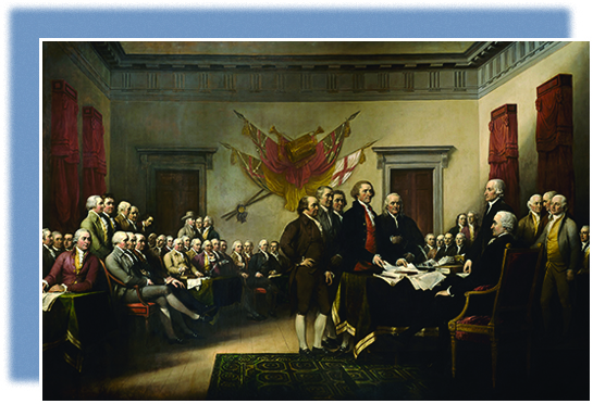 A painting shows members of the committee that drafted the Declaration of Independence presenting their work to the Continental Congress. Five men, including John Adams, Thomas Jefferson, and Benjamin Franklin, stand in front of a table at which other men are seated or standing. Jefferson is placing papers on the table. The room is filled with seated men, apparently the rest of the Continental Congress. British flags are mounted on the wall behind them.