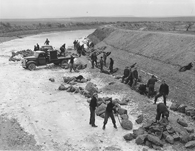 A photograph shows a group of CCC workers building a canal.