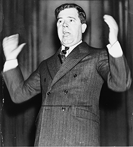 A photograph depicts Huey Long speaking and gesturing with his hands.