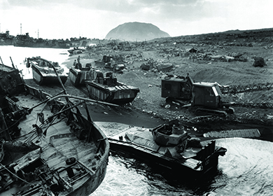A photograph shows American forces arriving ashore on the dark sands of Iwo Jima. Mount Suribachi is visible in the background.