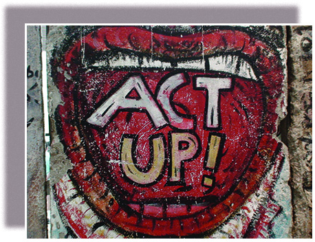 A panel of graffiti on the Berlin Wall shows a wide-open mouth, within which are the words “ACT UP!”